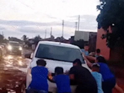 Crianças ajudam motorista a tirar carro de atoleiro em Campo Grande